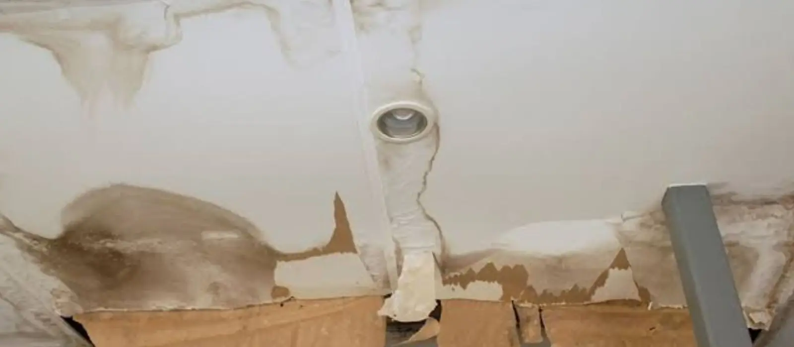 Water-damaged ceiling with peeling paint around a light fixture opening