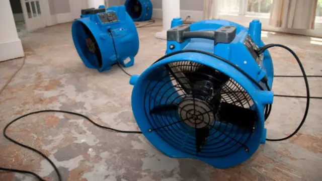 Blue air mover running on a floor after water damage